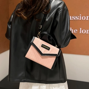 Sac à bandoulière rose à texture tissée avec poignées noires porté par un mannequin