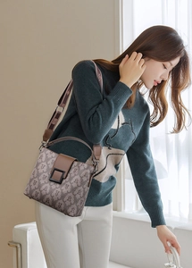 Close-up of vintage bucket bag featuring monogram print and wide fabric shoulder strap