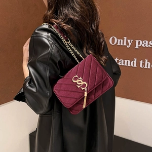 Chic burgundy velvet crossbody bag with V-shaped quilting and gold chain strap on model