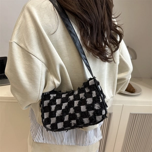 Sac à bandoulière rétro à damier noir et blanc avec bords effilochés sur un mannequin