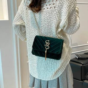 Green velvet crossbody bag with golden V-quilting and chain strap shown on model