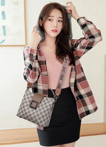 Detailed view of women's bucket bag with geometric prints and brown leather flap with strap