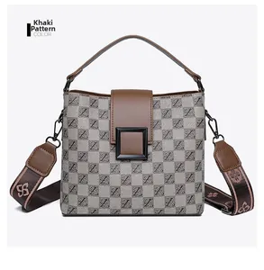 Detail of khaki grid patterned bucket bag with floral wide shoulder strap and metal buckle