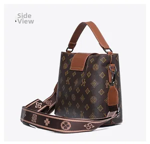 Detail side view of retro bucket bag with vintage monogram and woven shoulder strap