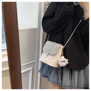 Detail of color-block crossbody bag with heart buckle and plush monster charm