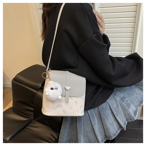 Detail of crossbody bucket bag with heart lock, cat print, and plush eye charm accessory