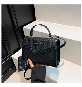 Close-up of black woven texture and Fashion Bag label on a stylish crossbody bag