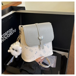 Detail of grey crossbody bag with blue cat prints, heart buckle and fluffy pompom