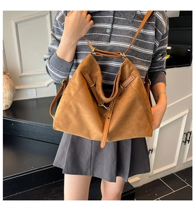Détail d'un grand sac cabas en daim marron avec boucle dorée et bandoulière en cuir