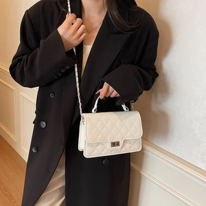White quilted chain crossbody bag with silver twist lock shown on a black blazer