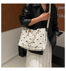 Detail of cream corduroy tote bag with black bow print and adjustable canvas strap