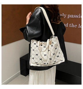 Detail of cream corduroy tote with black quilted bow pattern and beige canvas strap