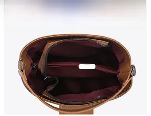 Detail view of the brown bucket bag showing two main compartments and a zipper pocket