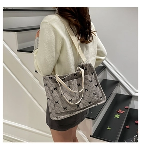 Detail of grey quilted tote bag with black bow patterns and dual shoulder straps