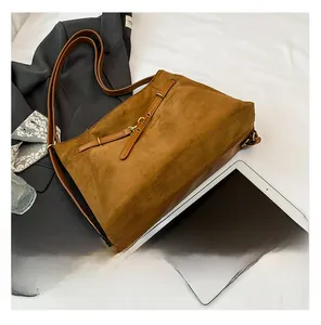 Détail d'un grand sac cabas vintage en daim marron avec boucle en cuir et fini mat élégant