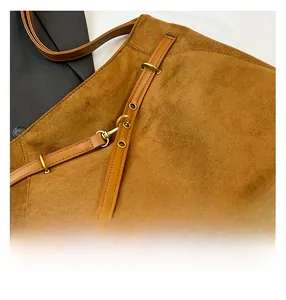 Gros plan sur la texture en daim marron avec boucle en métal doré et lanière en cuir