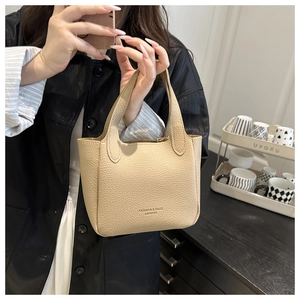 Detail of beige lychee pattern leather handbag with fashion lettering and sturdy handles