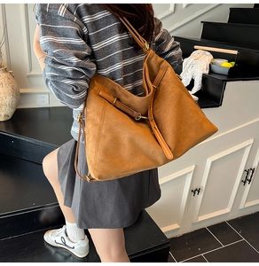 Gros plan sur le sac cabas en daim marron avec bandoulière et boucles dorées