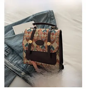 Close-up of geometric embroidery texture and brown leather handle on a vintage bag