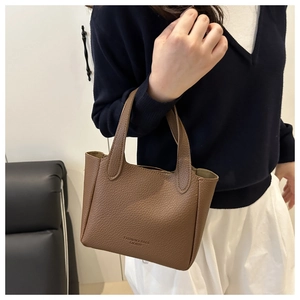 Detail of a brown lychee pattern leather bucket bag with FASHION & BAGS gold text