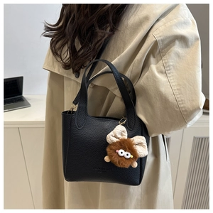 Détail du mini sac noir en cuir grainé avec breloque peluche et bandoulière amovible