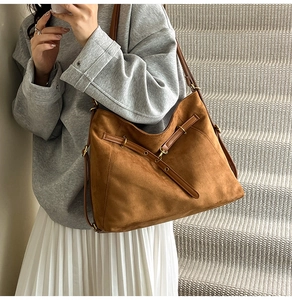 Détail du sac fourre-tout en daim caramel avec lanières en cuir et boucle métallique