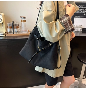 Détail d'un sac cabas noir mat avec ferrures dorées réglables dans un cadre de café