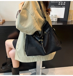 Détail du grand sac cabas en daim noir avec lanières en cuir et boucle dorée au café