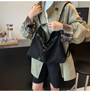 Gros plan d'un grand sac cabas noir mat avec bandoulière cuir et détails dorés
