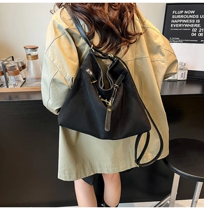 Détail du sac cabas noir avec longues bretelles et boucles en métal sur manteau kaki