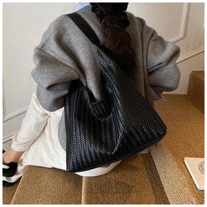 Close-up of the black woven texture and large capacity design of the faux leather tote bag