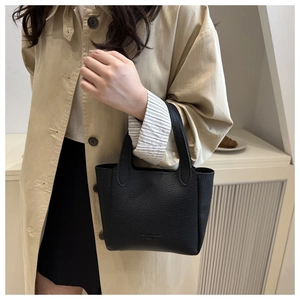 Detail of black lychee grain leather mini bucket bag with textured finish and fashion logo