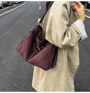 Photo de rue d'un sac cabas bordeaux en daim avec lanières en cuir et accessoires métalliques