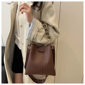 Detail of brown litchi pattern leather bucket bag with chain and woven strap