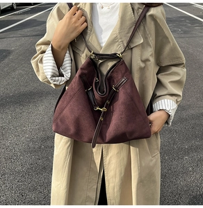 Gros plan détaillé d'un sac cabas en daim bordeaux avec bandoulière en cuir marron