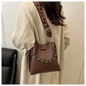 Detail of dark brown pebble leather bucket bag with chunky chain and jacquard strap