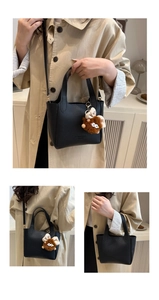 Detail of black lychee grain leather tote bag with a brown plush monster bag charm