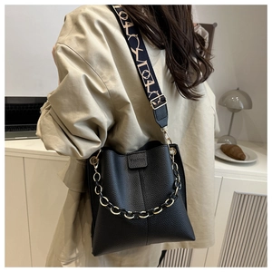 Detail of black pebbled bucket bag with geometric jacquard strap and gold chain strap