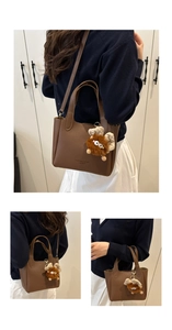 Detailed view of brown lychee grain tote bag with plush monster charm and strap