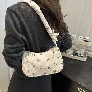 Chic corduroy underarm bag with black bow prints worn by a model in a side view