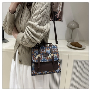 Detail of retro geometric woven pattern handbag with brown leather trim and gold buckle