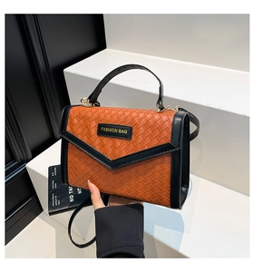 Detail of woven texture handbag in orange and black with adjustable shoulder strap