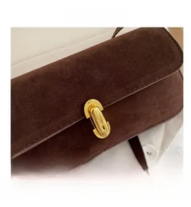 Gros plan d'un sac baguette en daim marron avec fermoir ovale doré vintage