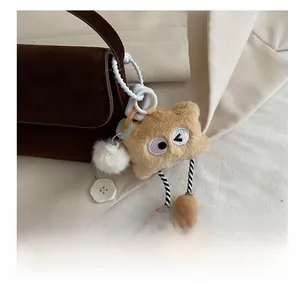Gros plan d'un pendentif monstre en peluche kaki sur un sac à bandoulière marron foncé