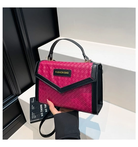 Detail of woven texture handbag with V-shaped flap design and fashion logo tag