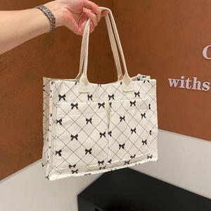 Corduroy cream tote bag with black bow lattice pattern and dual front exterior pockets
