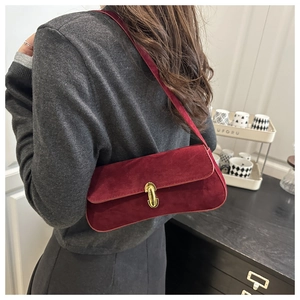 Detail of burgundy faux suede shoulder bag featuring a gold metal twist lock closure