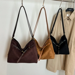 Trois sacs hobo en daim en café, caramel et noir suspendus sur un cintre de mode élégant