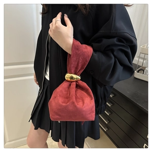 Détail du sac seau en daim rouge avec poignée boule dorée et fermeture à cordon