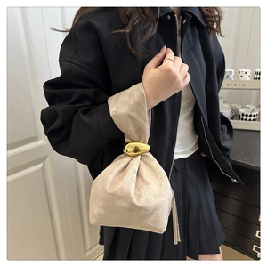 Gros plan du sac seau en velours champagne avec une poignée métallique dorée en forme d'œuf